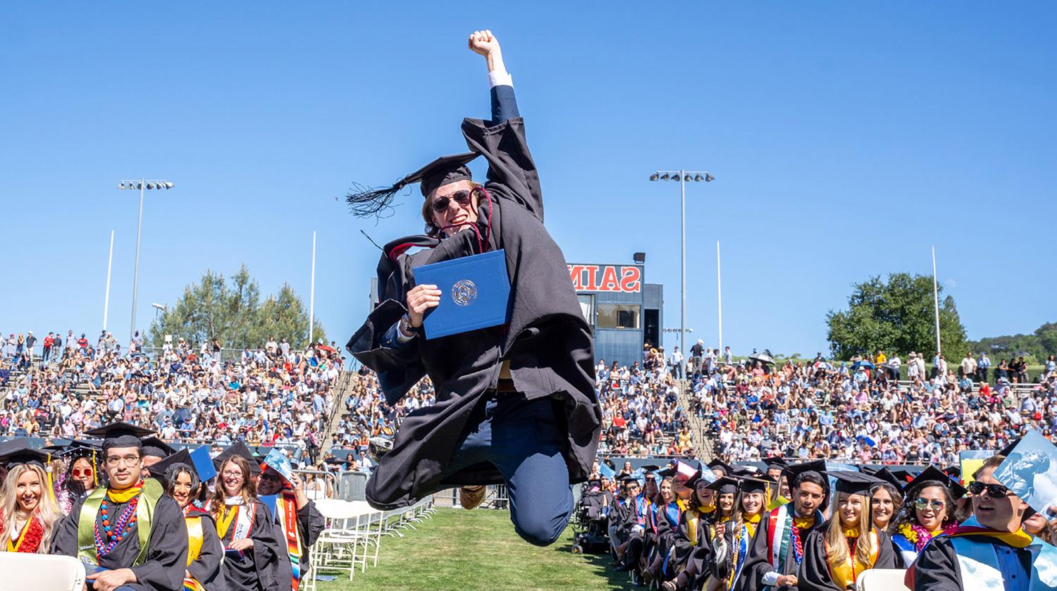 student jumping for joy on sunny graduation day