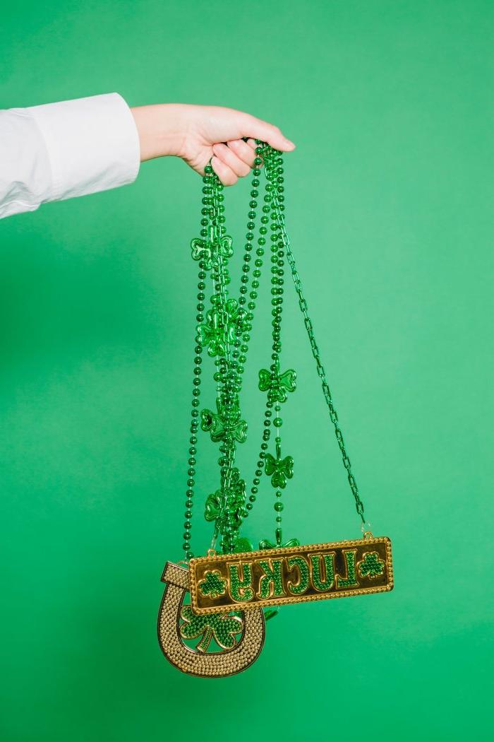 A hand holds St. Patrick's Day necklaces with a horseshoe and "lucky"